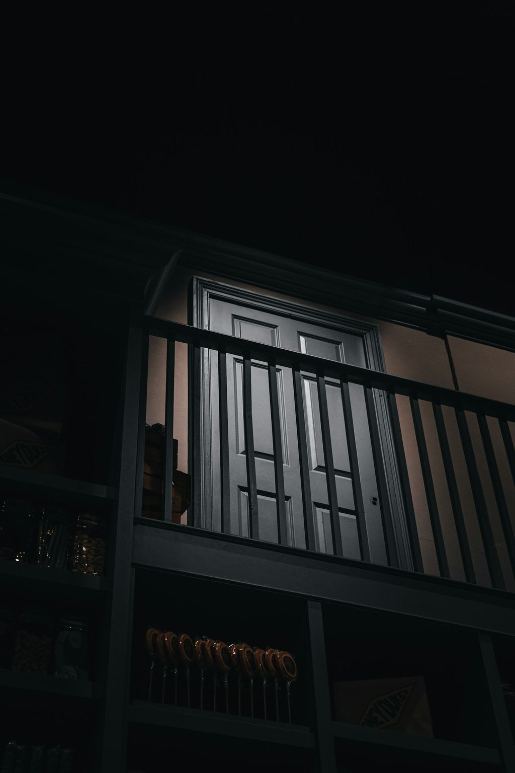 Oszklone drzwi balkonowe na piętrze budynku, nocą, za balustradą
