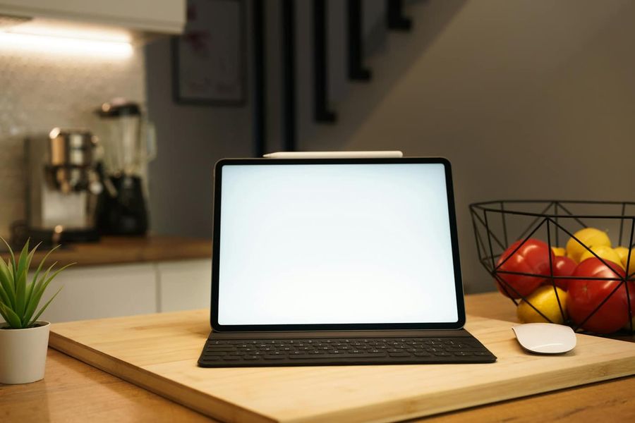 Tablet z klawiaturą na drewnianej desce w kuchni, obok koszyk z owocami