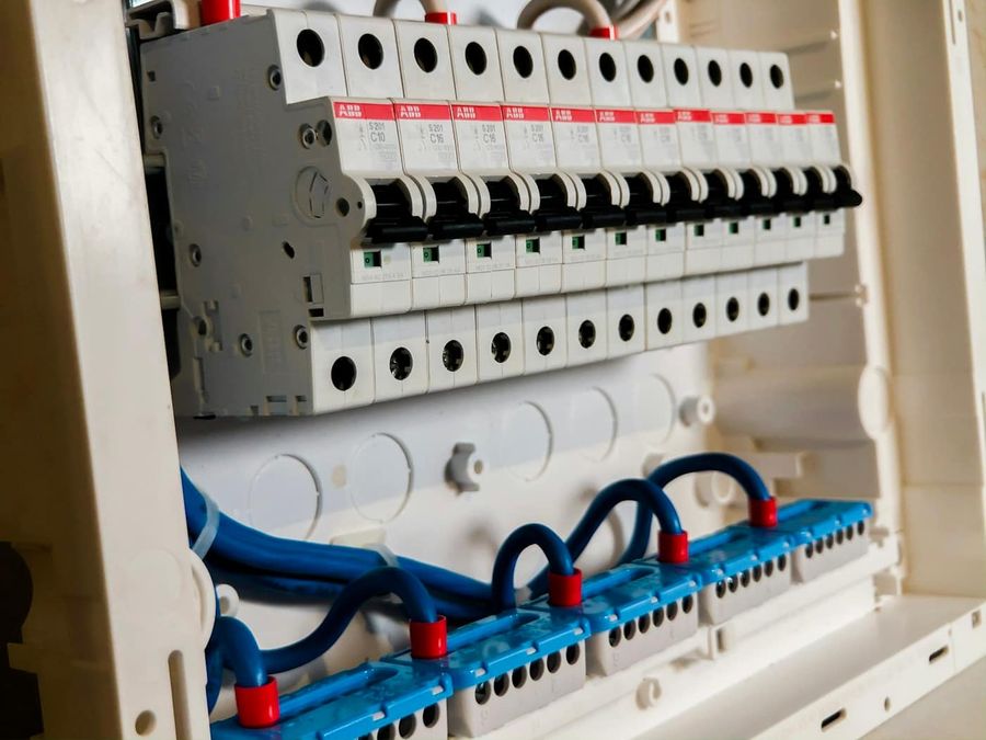 Wnętrze rozdzielnicy elektrycznej z rzędem wyłączników i przewodami