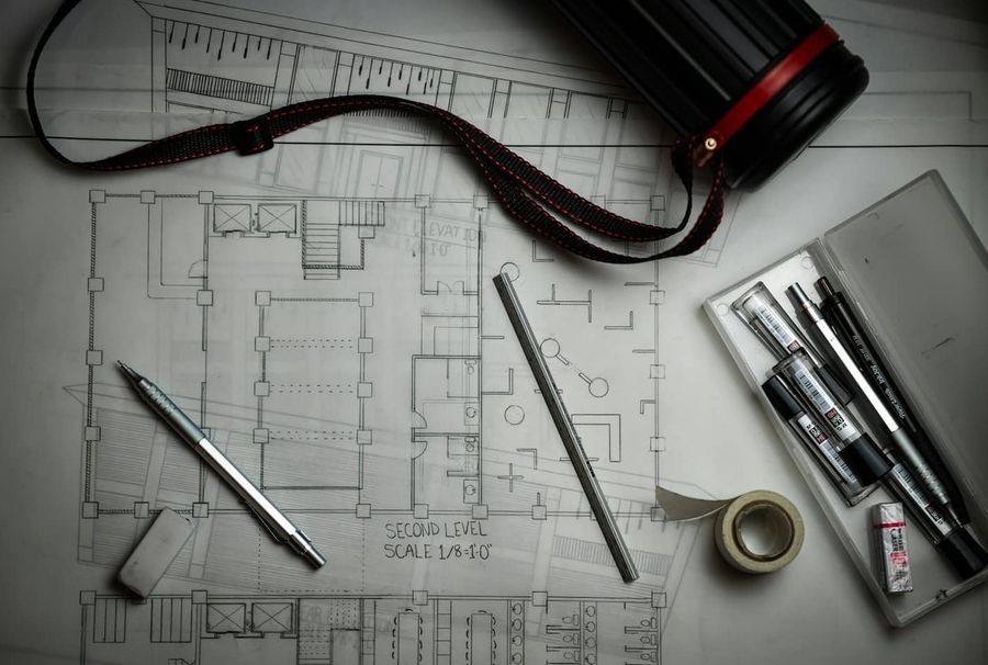 Rysunki techniczne na biurku z ołówkami, linijką i tubą na plany