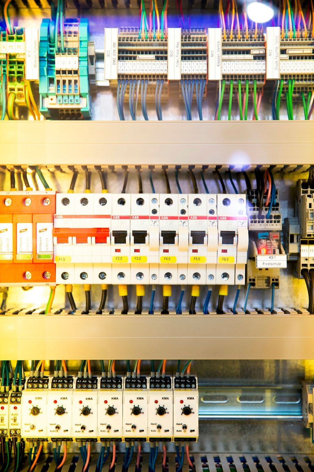 Otwarta rozdzielnica elektryczna z rzędem wyłączników i kolorowymi przewodami