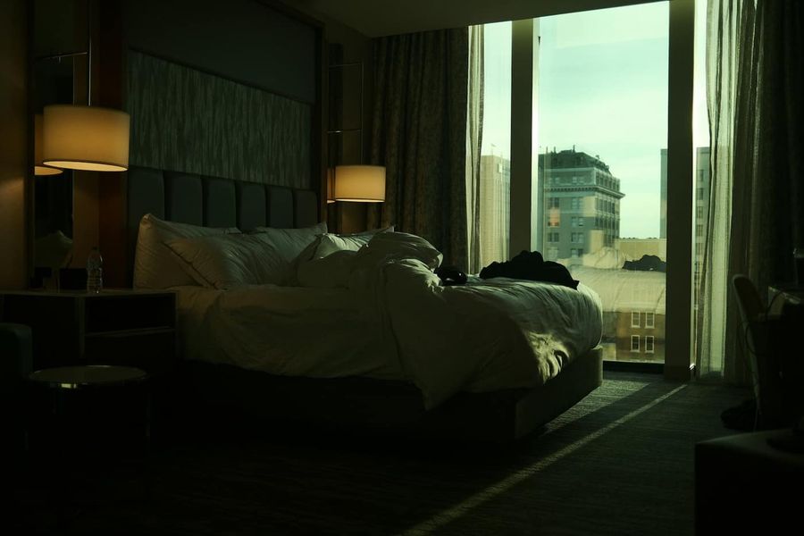 Pokój hotelowy o zmierzchu z dużym oknem i widokiem na miasto