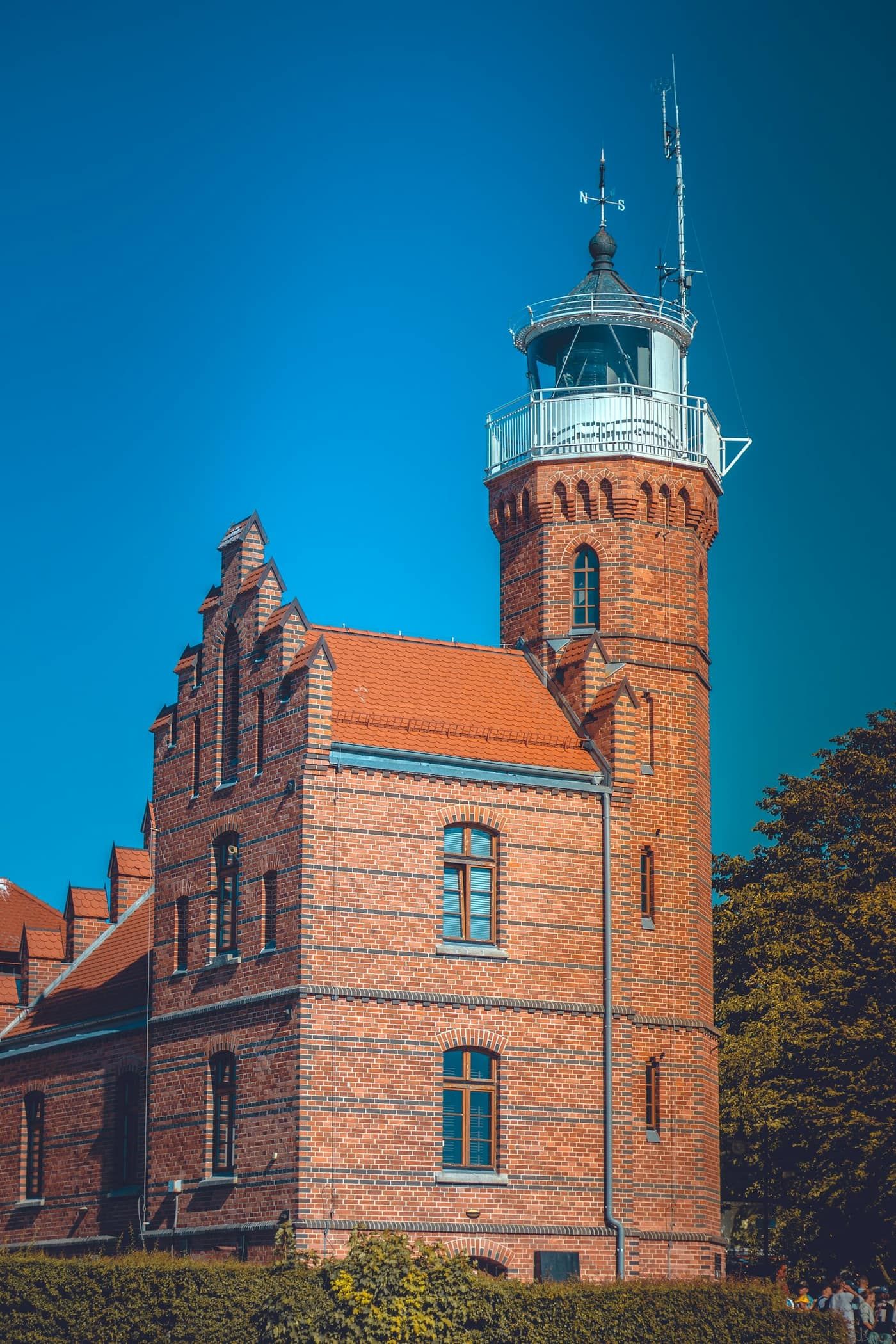 Ceglana latarnia morska z wieżą na wybrzeżu, na tle błękitnego nieba
