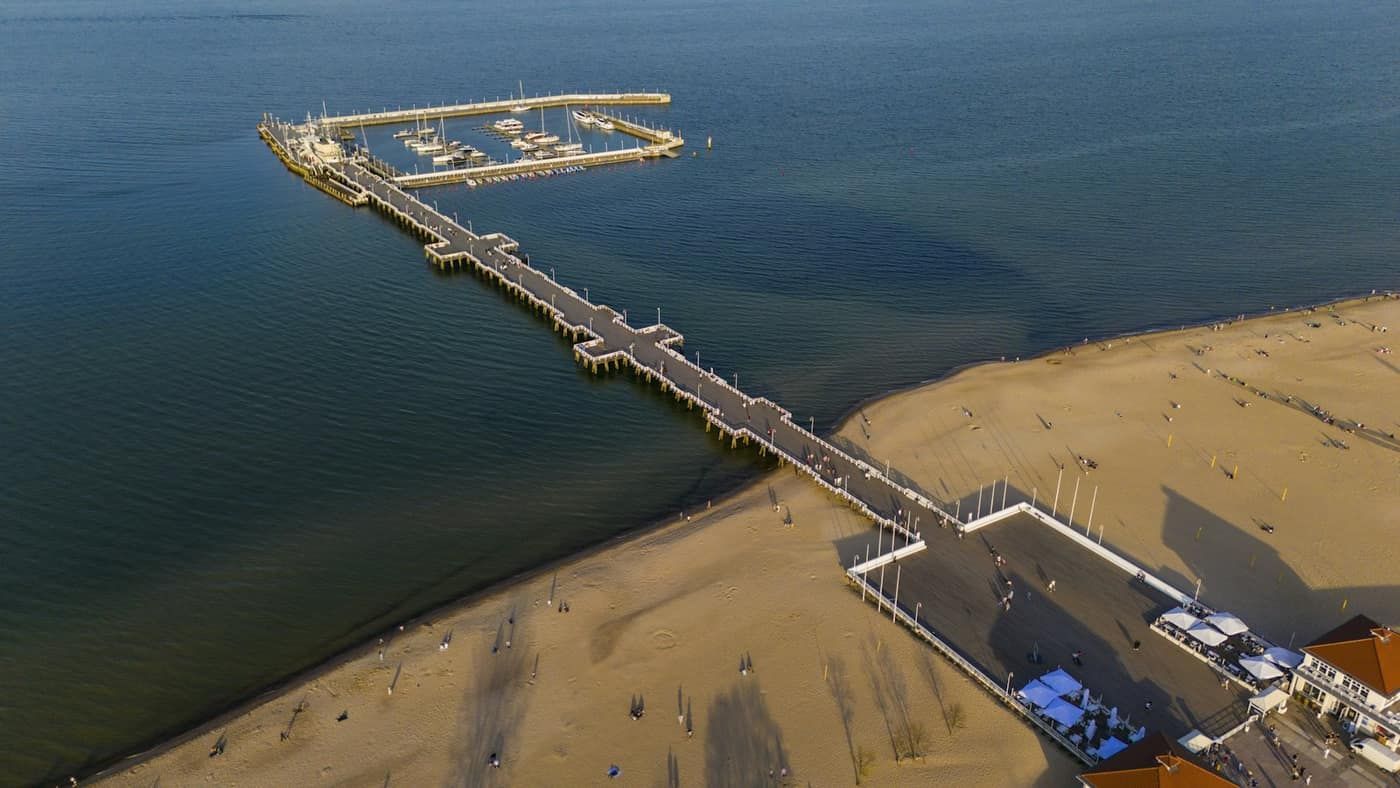 Molo w Sopocie z lotu ptaka, z mariną na końcu i plażą przy brzegu